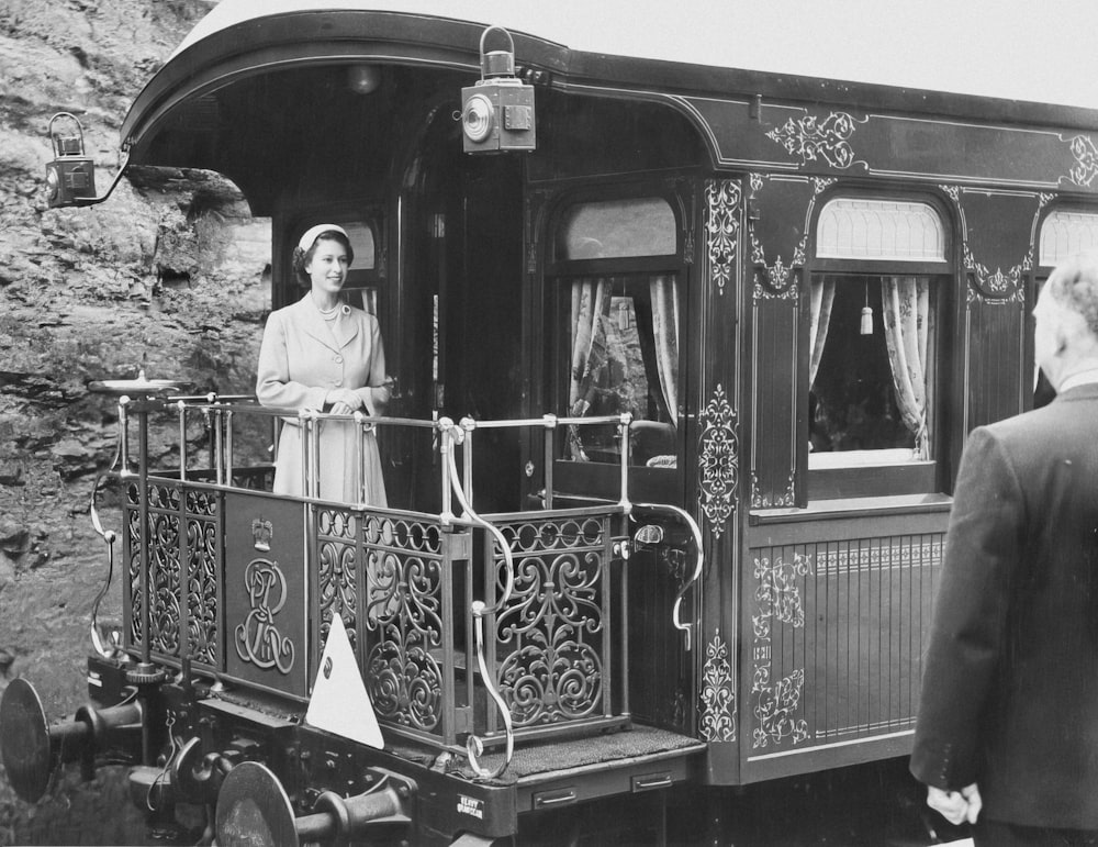 a black and white photo of a woman standing on a train