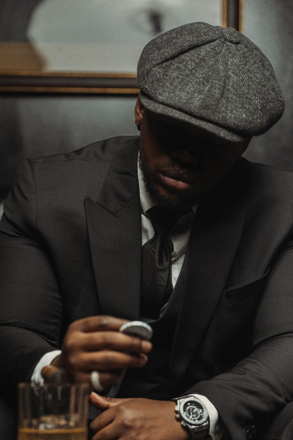 a man in a suit and hat looking at his cell phone