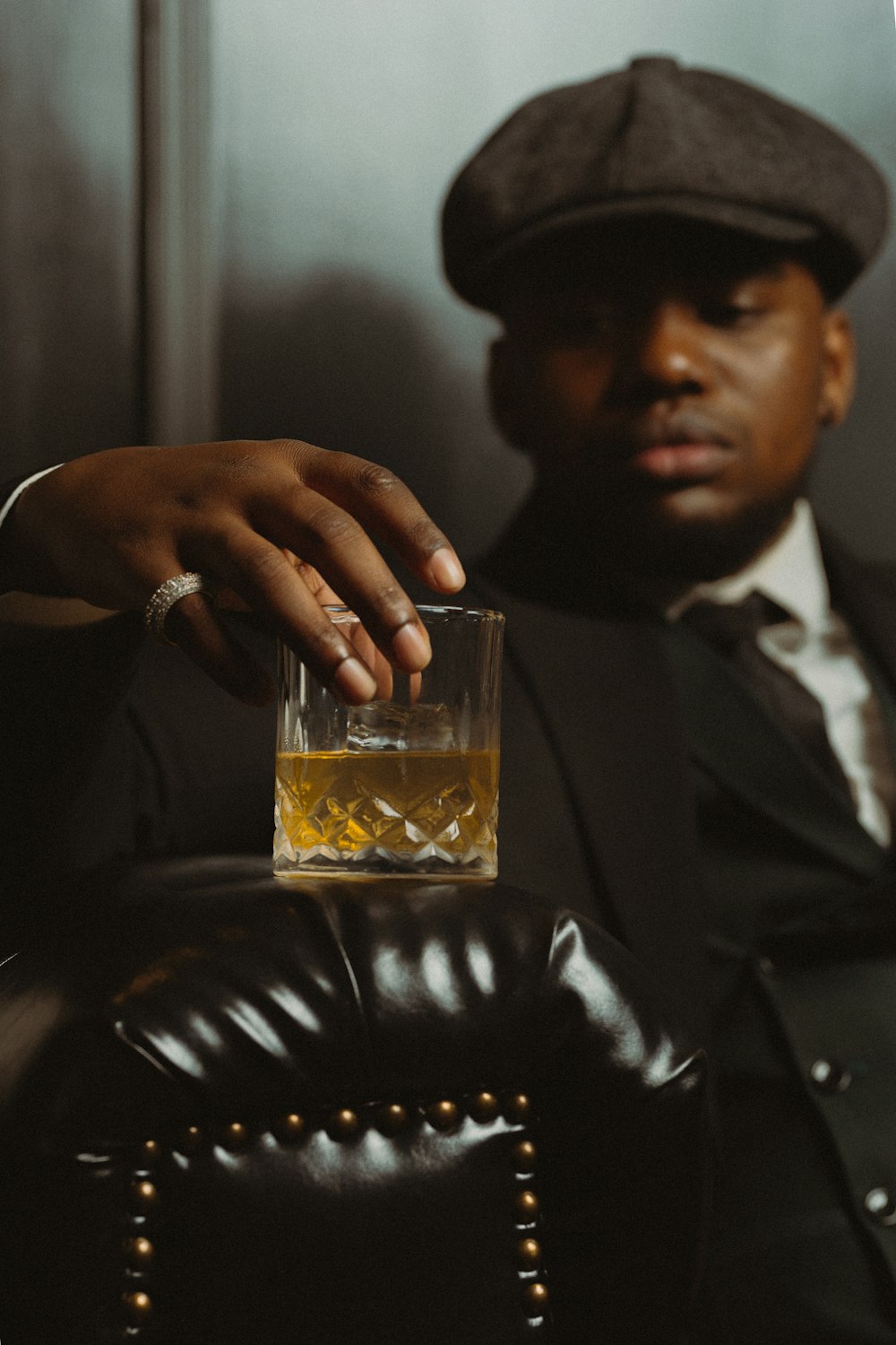 a man in a suit holding a glass of whiskey