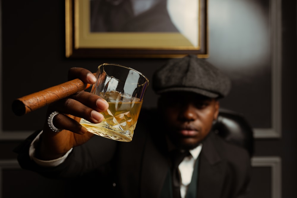 a man holding a cigar and a glass of whiskey