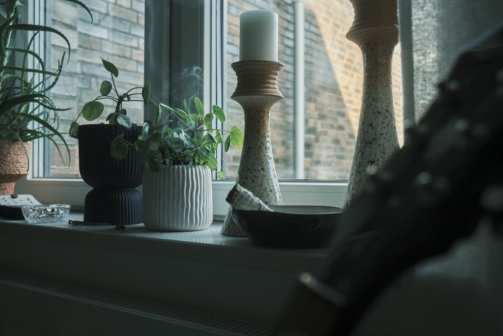 a window sill filled with potted plants next to a candle
