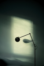 A minimalist floor lamp illuminating a reading nook by the window.