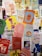 A collection of colorful posters and artwork covers a surface, featuring various illustrations, text in Portuguese, and vibrant designs. The posters include images of drinks, abstract shapes, human figures, and a mix of colors and styles, creating a lively and artistic collage.