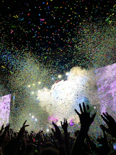 a crowd of people at a concert with confetti in the air