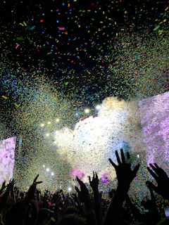 a crowd of people at a concert with confetti in the air
