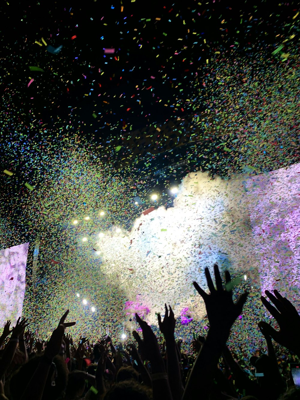 a crowd of people at a concert with confetti in the air