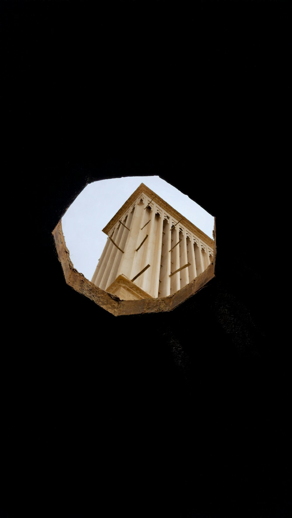 a view of a clock tower through a hole in the wall