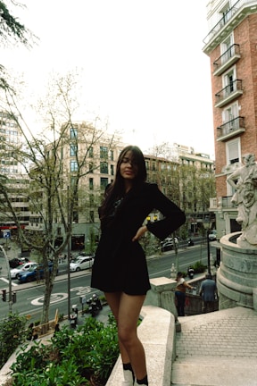 An outdoor shot of a confident woman in a sleek black outfit against a soft urban backdrop.