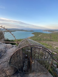 a bird cage sitting on top of a large rock