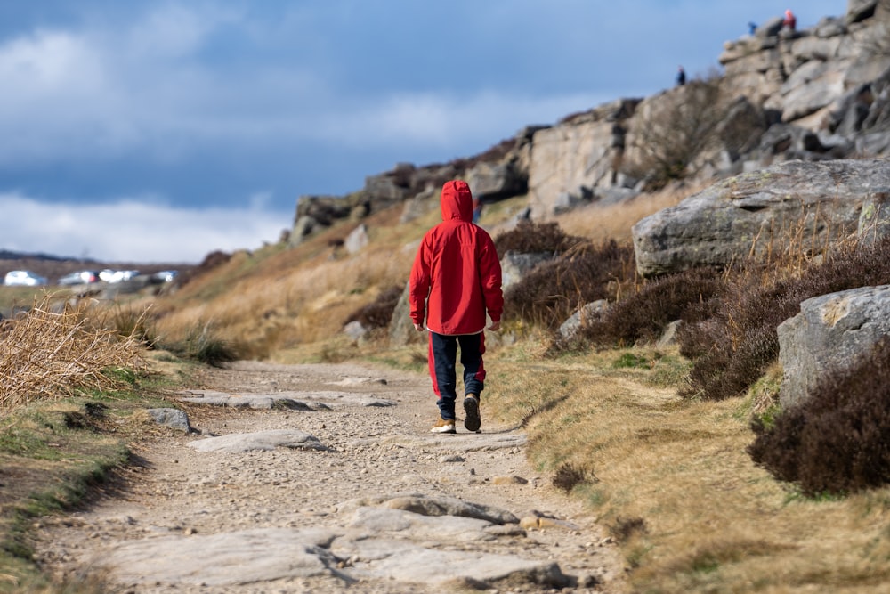 a person in a red jacket walking down a dirt road