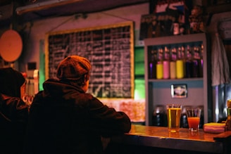 Cozy bar interior with warm lighting and people enjoying drinks.