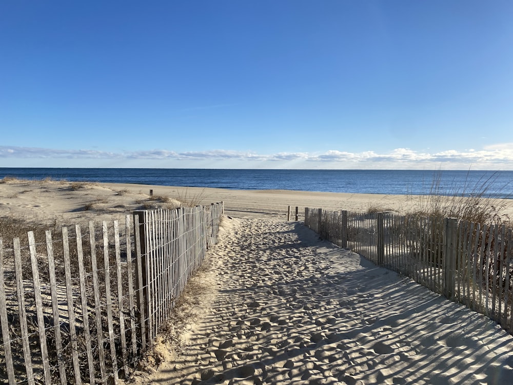 a sandy path leading to the beach with the ocean in the background