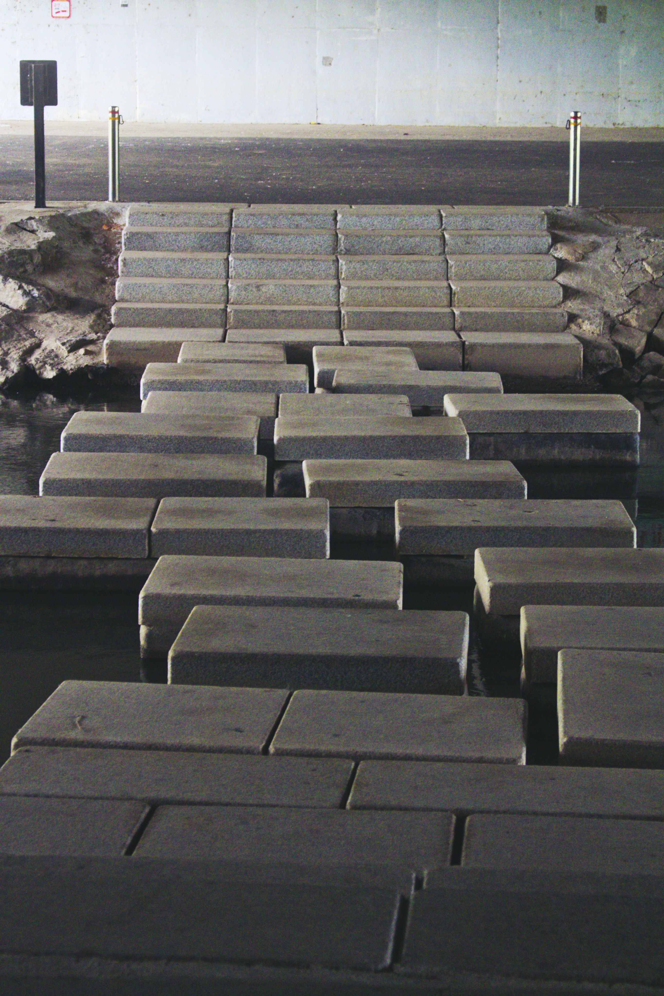 a walkway made out of cement blocks next to a body of water