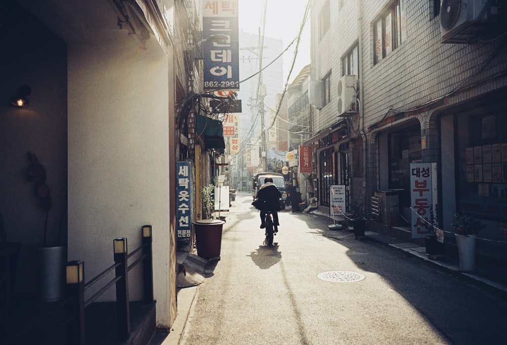 a man riding a bike down a street next to tall buildings