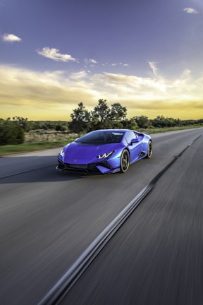 A quiet country road with a shiny car cruising smoothly under a clear blue sky