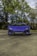 A luxurious sports car parked on a scenic road with a clear blue sky.