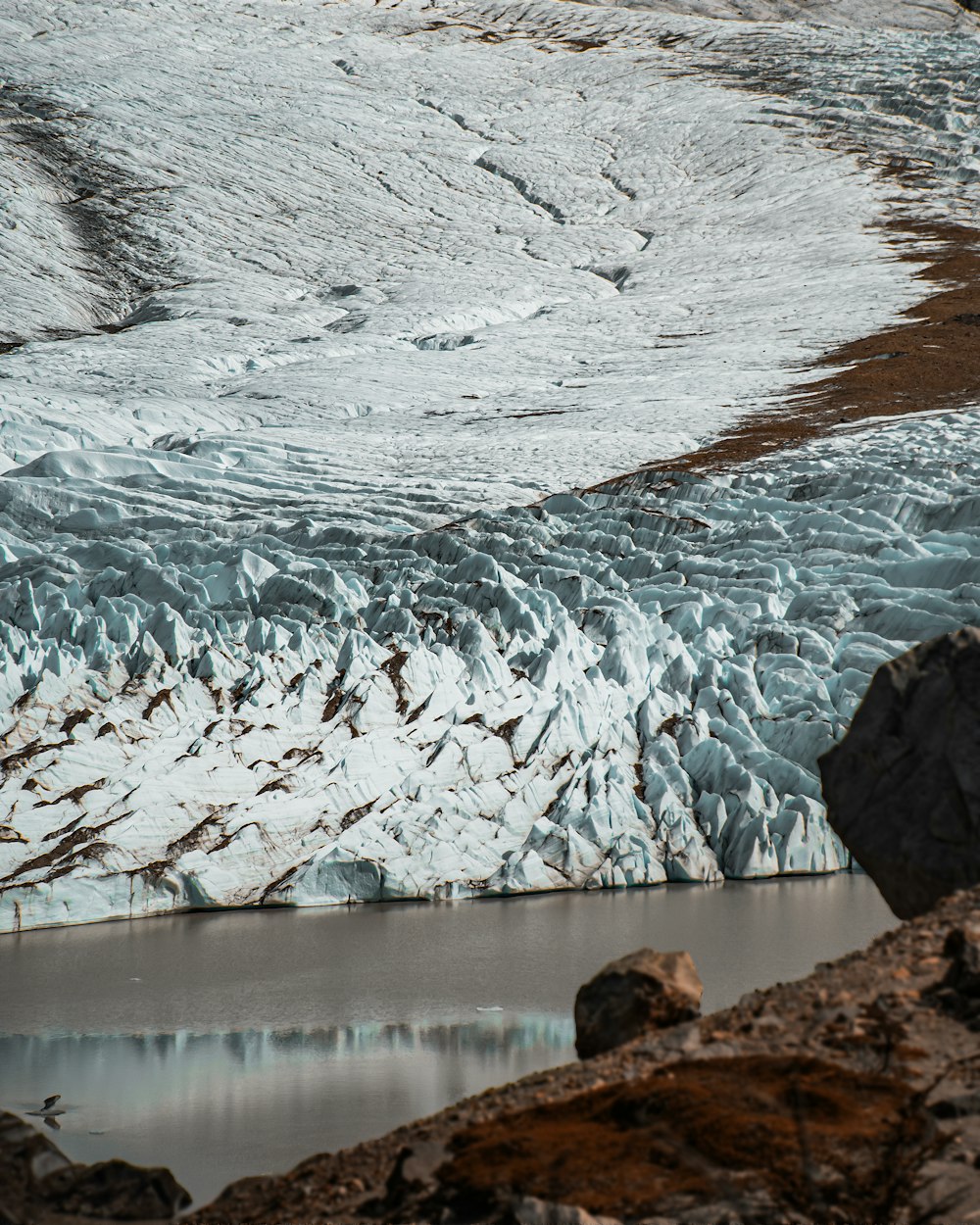 Un uomo in piedi sulla cima di una montagna vicino a un ghiacciaio