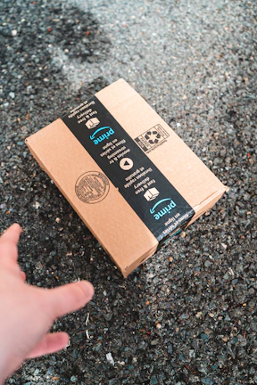 a hand is pointing at a box on the ground