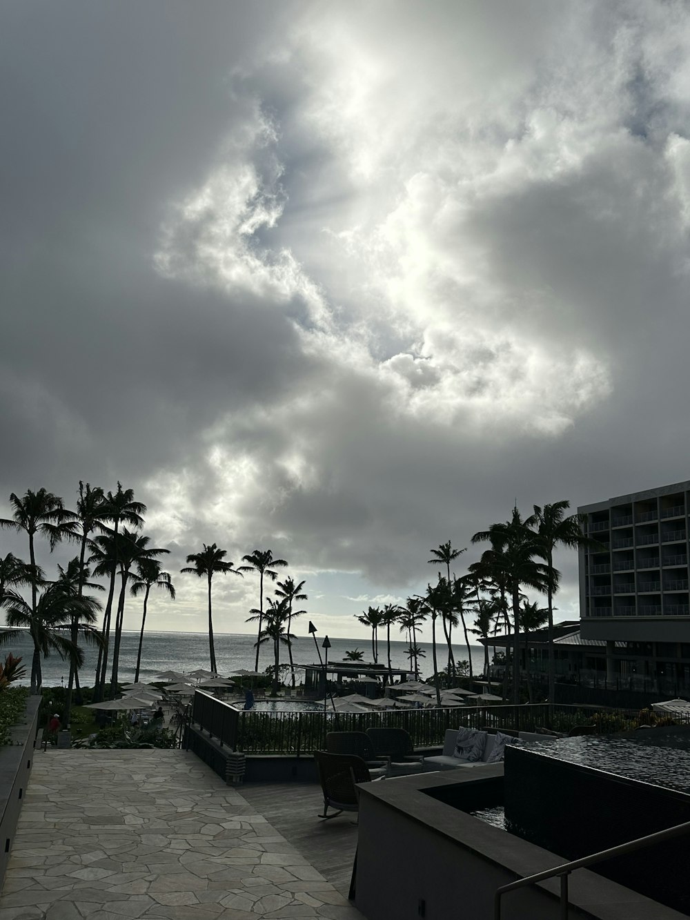 a cloudy sky over a beach with palm trees