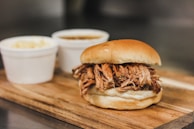 Close-up of juicy pulled pork piled high on a toasted bun with coleslaw.
