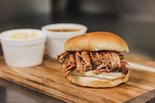 A smoky pork sandwich with fresh ingredients displayed on a plate.