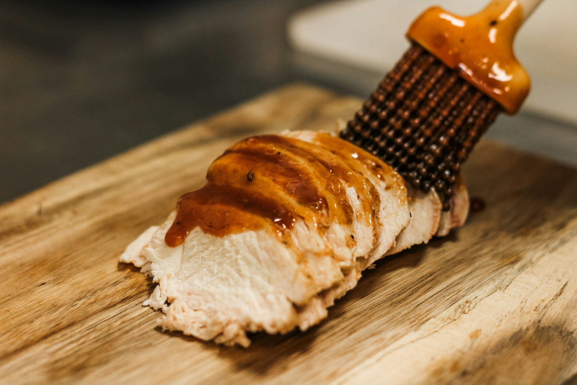 a wooden cutting board topped with a piece of meat covered in sauce