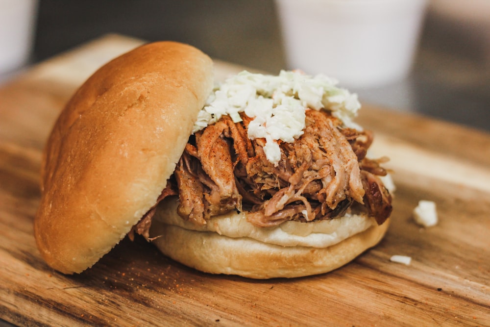 a pulled pork sandwich on a wooden cutting board