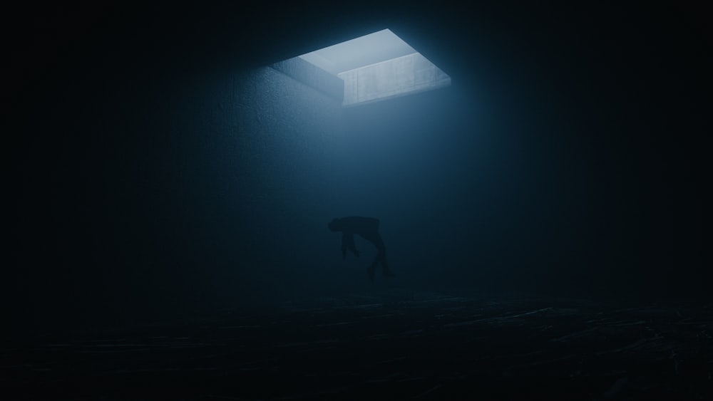 una persona in piedi in una stanza buia sotto una luce