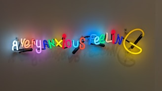 Neon text art installation displaying the words 'A very anxious feeling' in colorful, illuminated letters mounted on a plain wall.