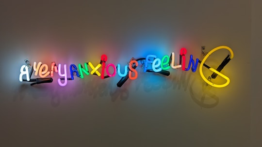 Neon text art installation displaying the words 'A very anxious feeling' in colorful, illuminated letters mounted on a plain wall.