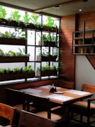 A cozy dining area with a wooden table and plants.