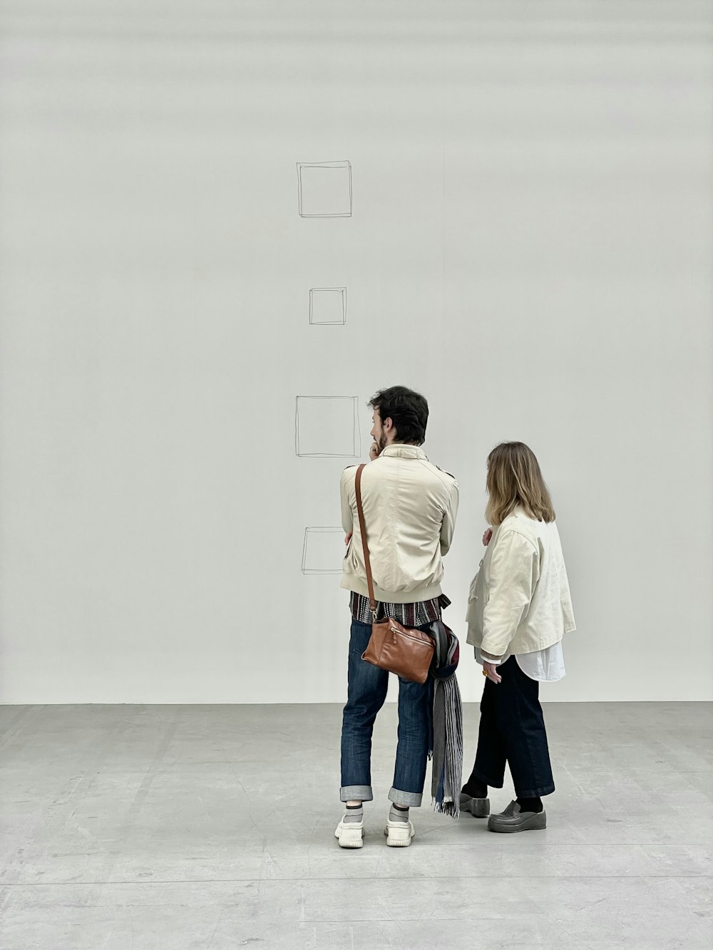a man and a woman standing in front of a white wall