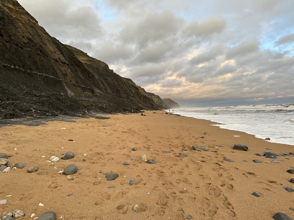 a sandy beach with a rocky cliff in the background