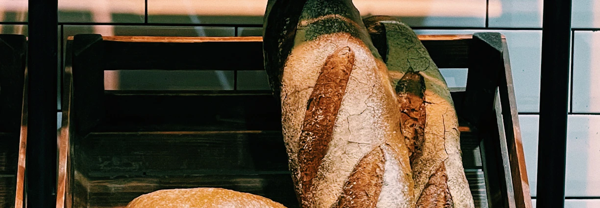 Warm, rustic bakery interior with fresh artisan breads cooling on wooden shelves.