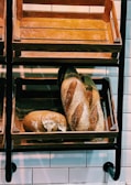 Baker arranging freshly baked goods on shelves in a bakery.