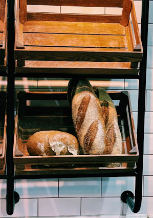 Warm bakery interior with fresh bread loaves displayed on wooden shelves.