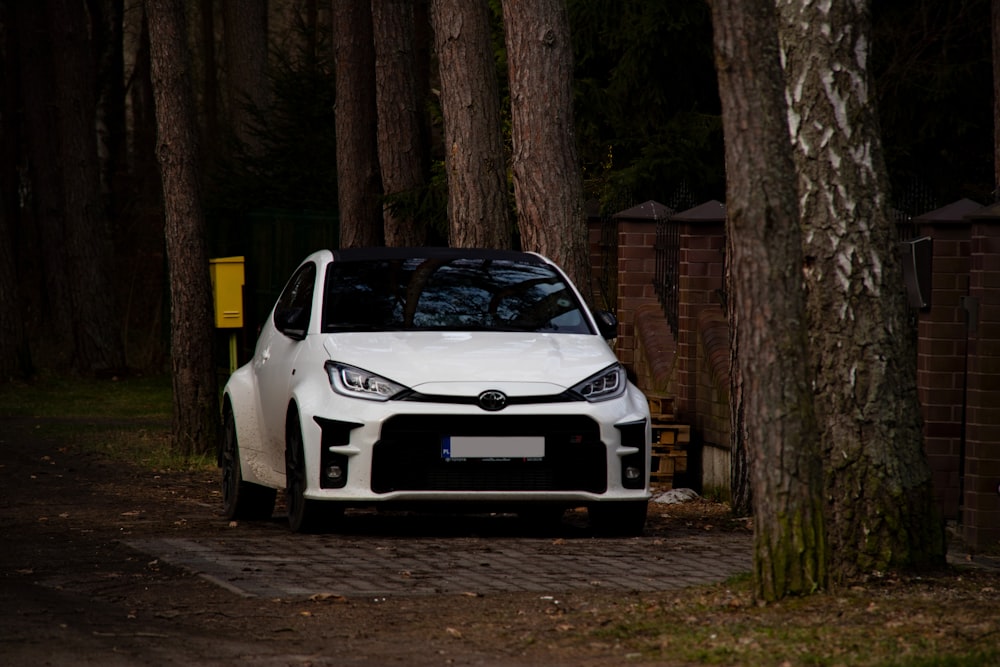 a white car parked in front of some trees
