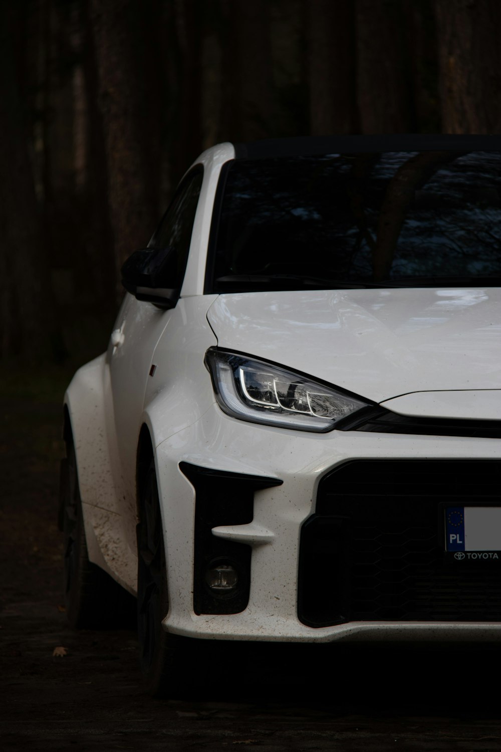 a white car parked in front of some trees