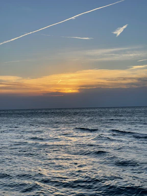 A serene seaside view at sunset with gentle waves and a teal sky reflecting the colors of the sea.