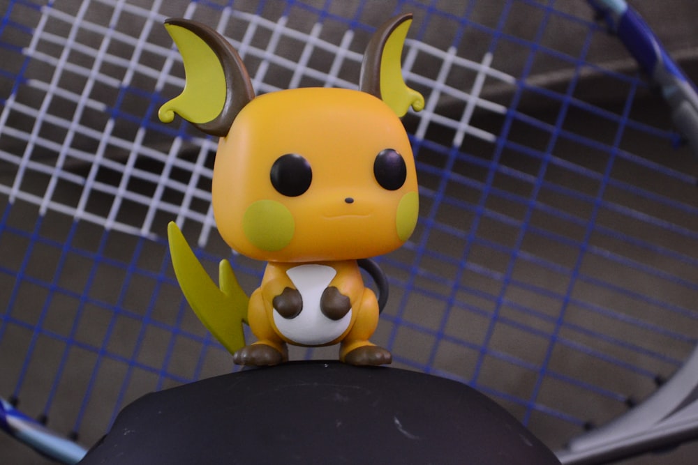 a yellow and black figurine sitting on top of a tennis racquet