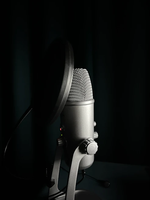 Close-up of a professional microphone with pop filter in a softly lit recording booth