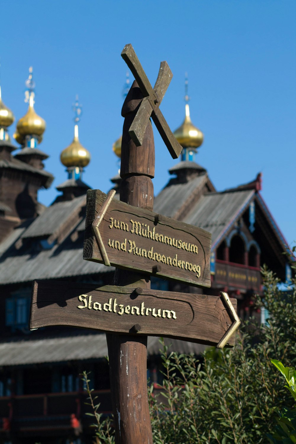 a wooden sign pointing in different directions in front of a building