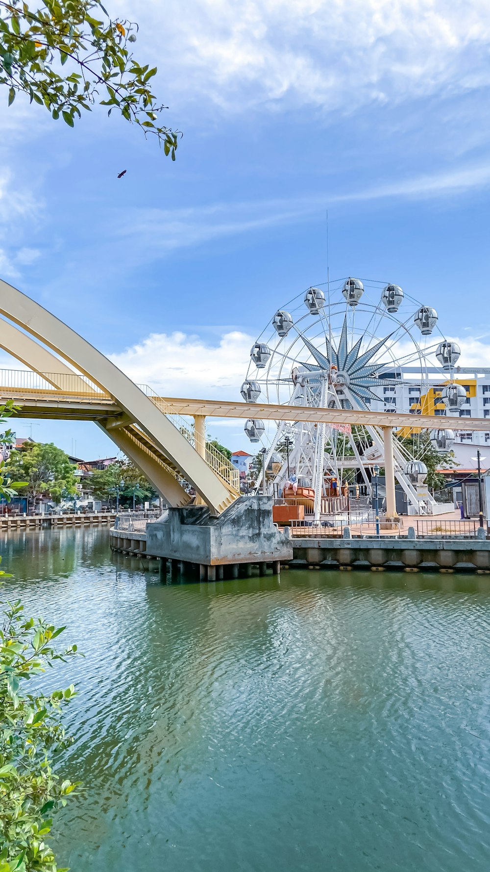 a ferris wheel sitting on top of a river next to a bridge