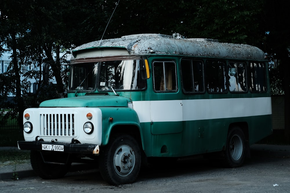 a green and white bus parked on the side of the road