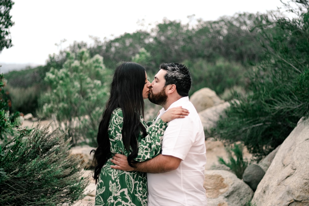 a man and a woman kissing in front of some rocks