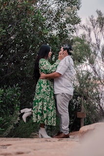 Two people embracing tenderly against a backdrop of natural green hues.