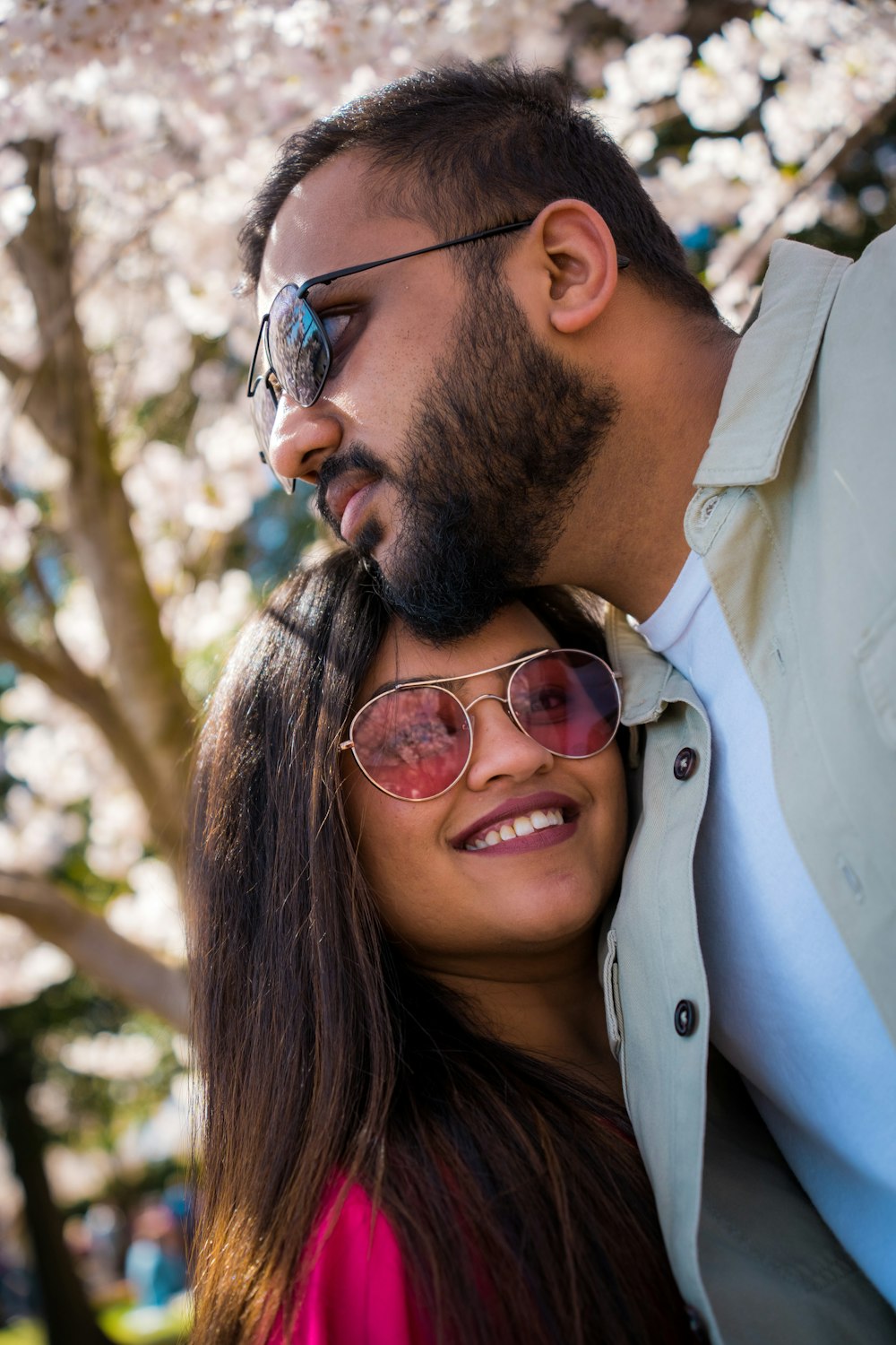 a man and a woman standing next to each other under a tree