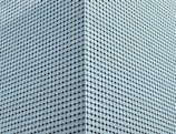 A large facade is covered with a uniform pattern of round, light blue tiles that create a textured, geometric appearance. The tiles are densely packed, aligning in diagonal rows that emphasize the modern architectural design.
