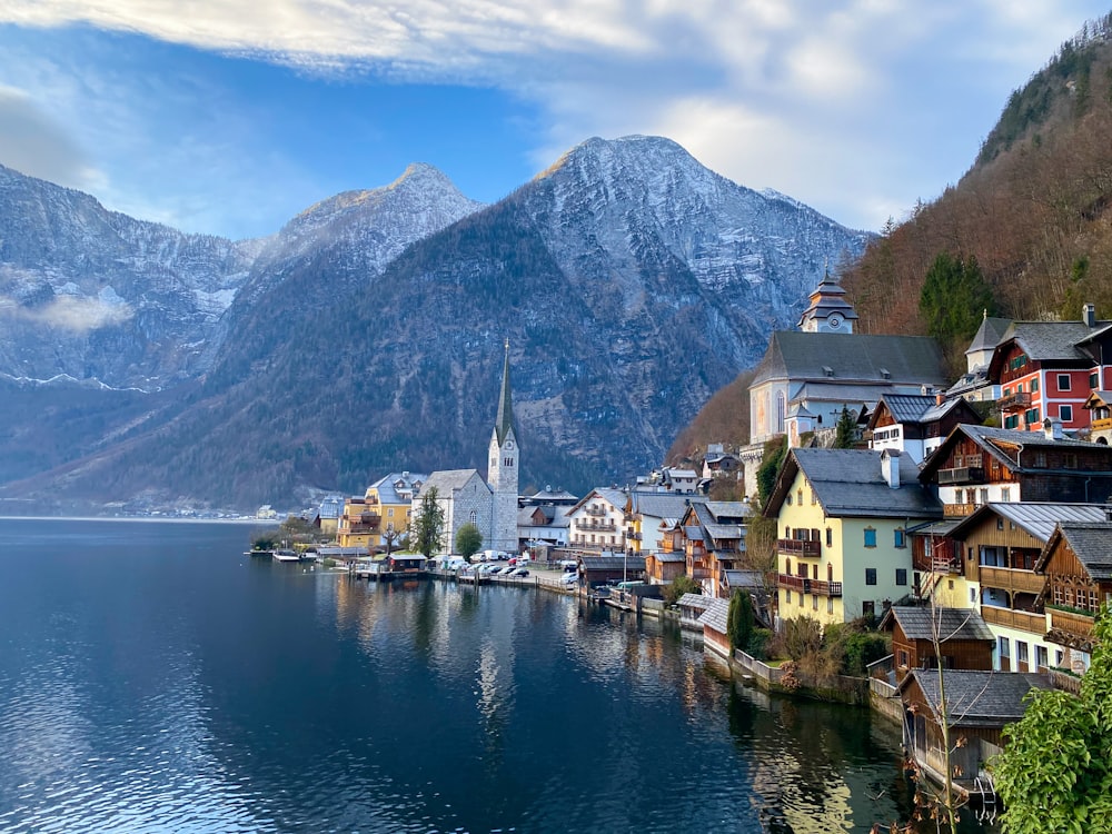 a village on the shore of a lake with mountains in the background