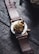 A leather-strapped watch featuring a detailed, golden lion motif on the back of the case. The design includes intricate rose engravings surrounding the lion's head, creating a luxurious and artistic look. The watch is placed on a dark, textured wooden surface.